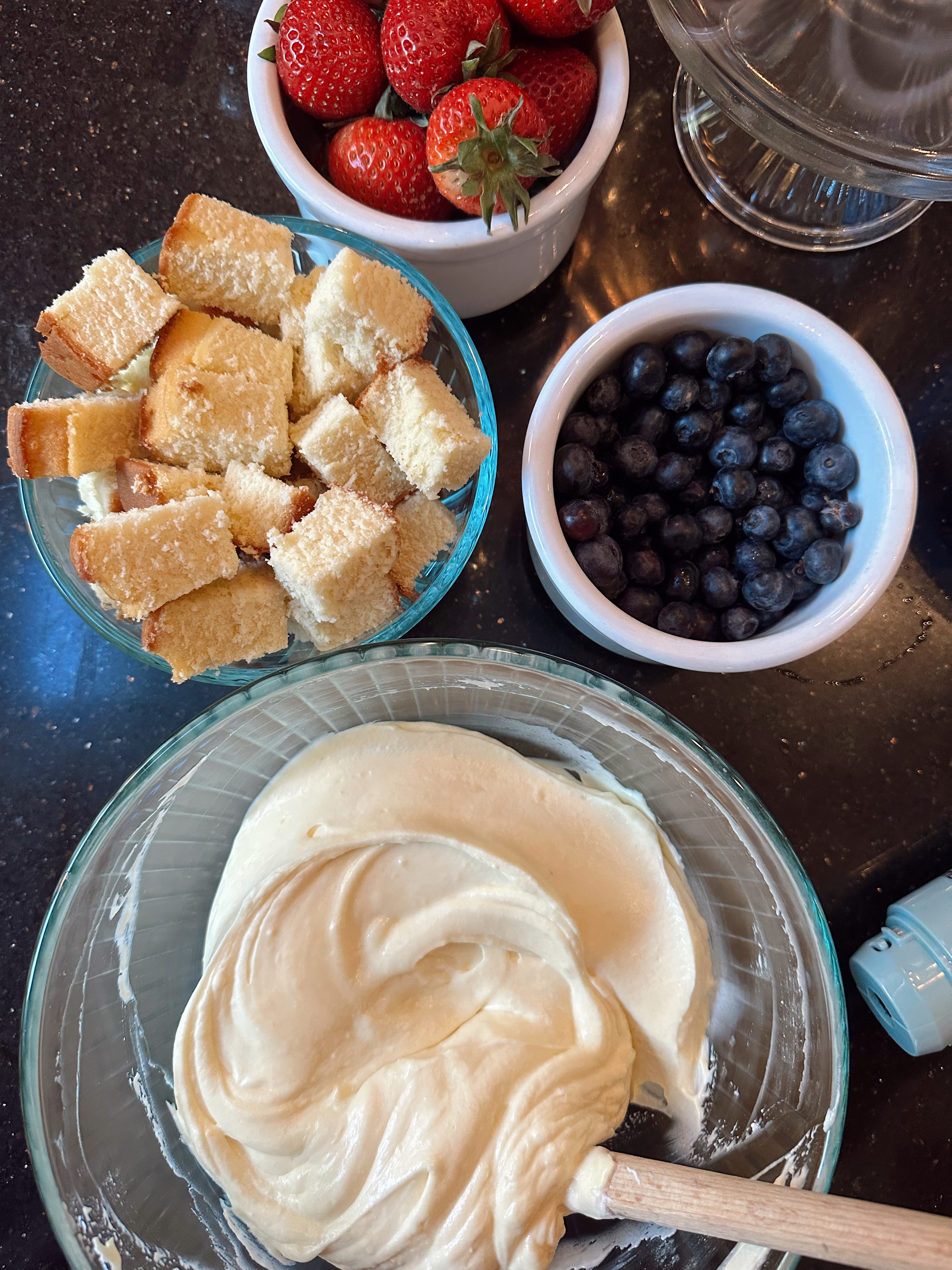 cream folded together with cake pieces and berries on the side