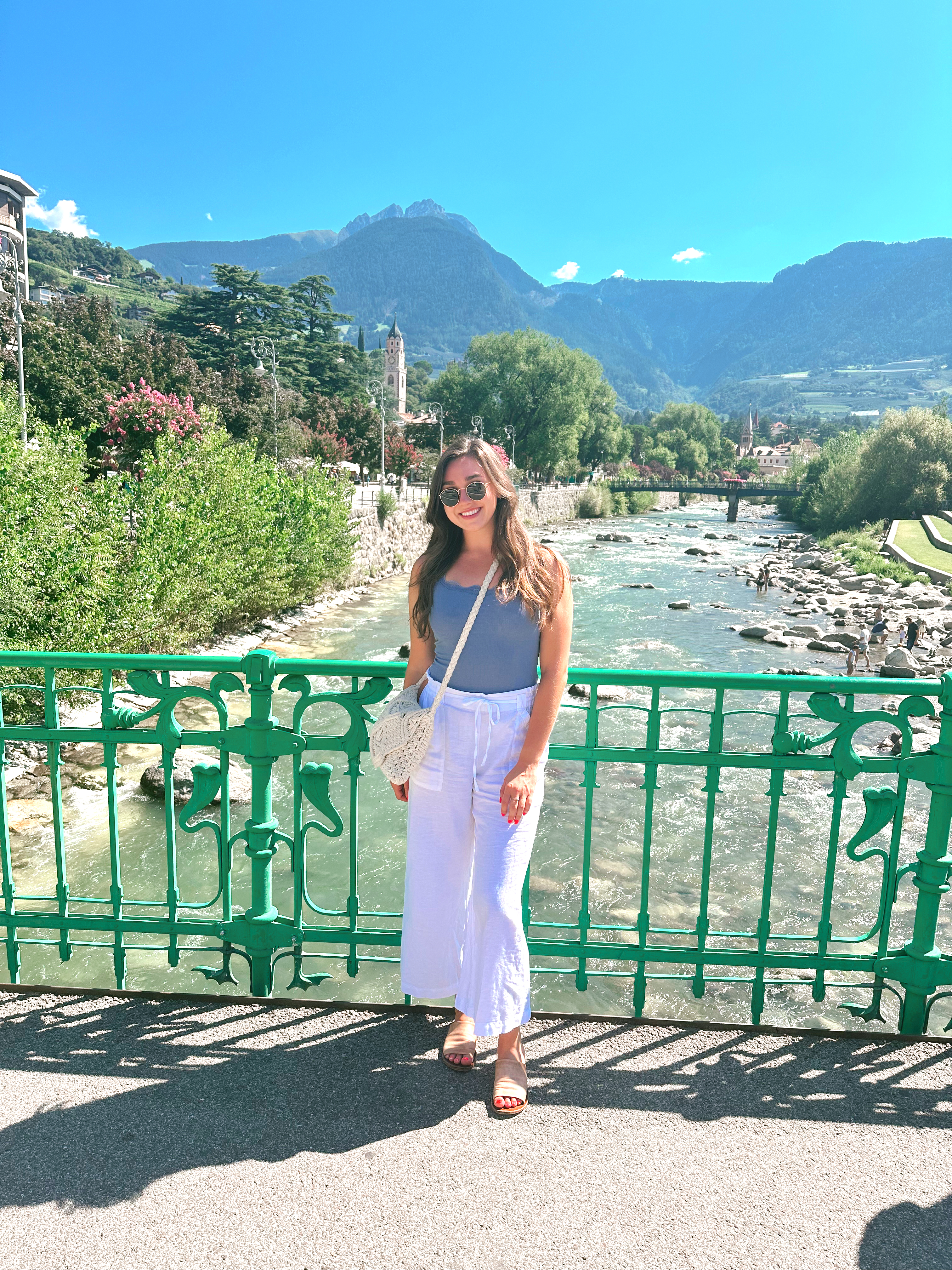 Ava standing on a bridge over a river in Merano, Italy