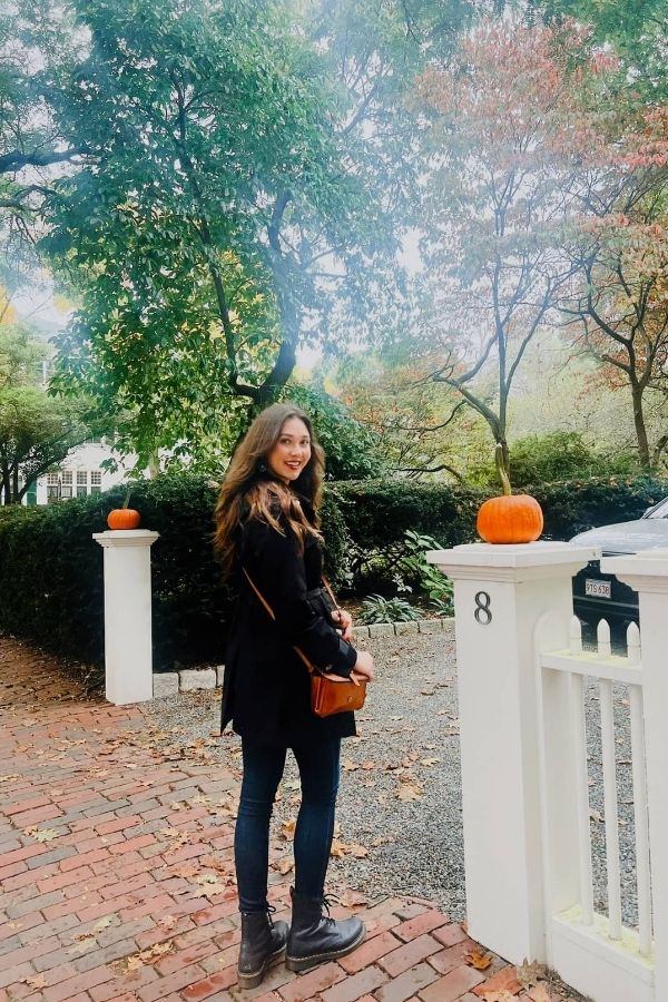 Ava standing in streets of Salem with trees and pumpkins